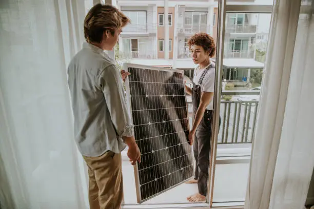 Photo of Asian Gay couple are installing solar panel on the balcony of the house-stock photo