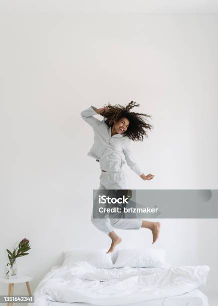 Mixed Race Woman Jumping Over Bed In Morning Stock Photo - Download Image Now - Bed - Furniture, Jumping, Hotel