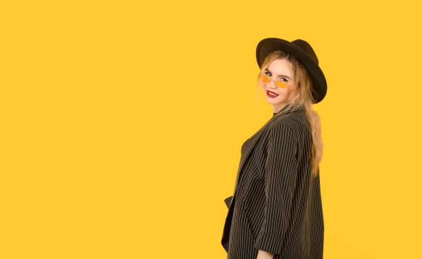 istock Young girl posing on yellow background half body direct look back side view 1351642366