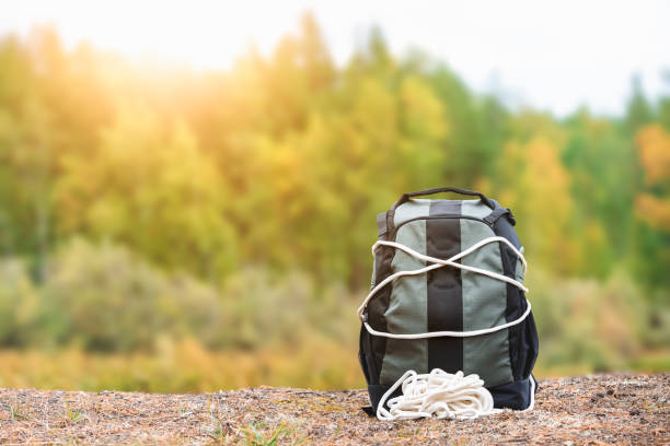 istock Tourists backpack is wrapped with thick rope on the forest shore. Hike equipment. 1351648410
