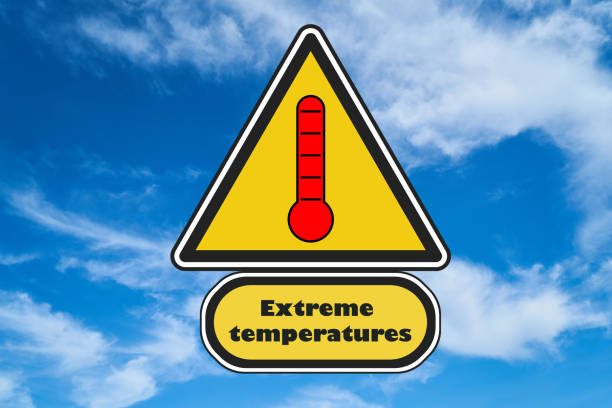Road triangle yellow sign with a red thermometer and extreme temperatures text written on. Sky in the background. Concept for climate change, global warming.