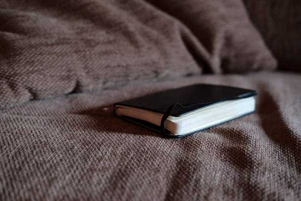 istock Notebook in a black leather-bound lies on the couch, in natural light. 1351653247