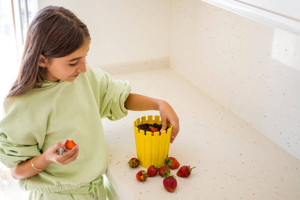 istock Beautiful girl sprouting strawberry again in soil 1351654325