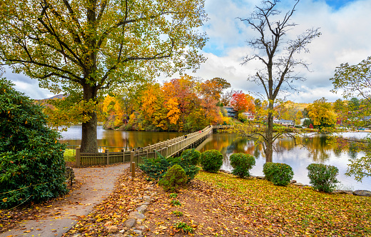 Lake Junaluska in autumn colors. People walking on the bridge over the  lake. Autumn lake in colorful forest.  Blue Ridge Mountains. Near Asheville, North Carolina, USA.