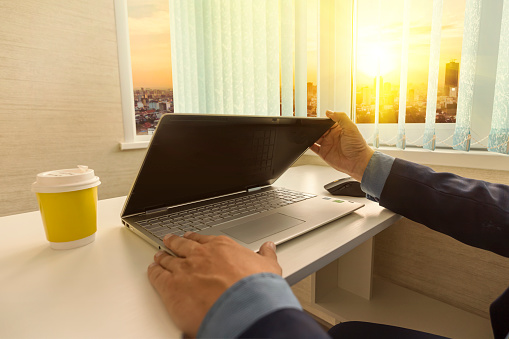 office desk table. man opening modern laptop near mouse on white background. The beginning of the working day. Completion of the concept. sunset outside the window