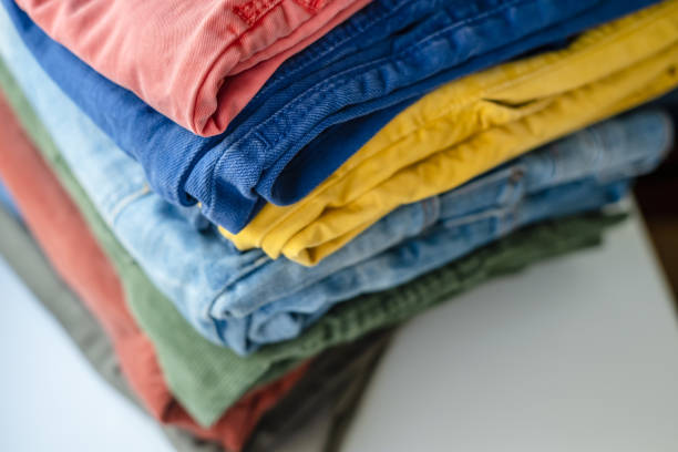 istock Neatly folded pants and jeans in bright colors on a white shelf. 1351658743