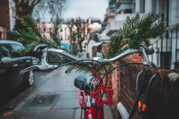 A bicycle parked at the entrance to the house decorated with Christmas tree branches and ornament near the house in street of Notting Hill, London, UK