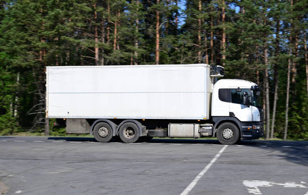 istock White cargo refrigerator driving at high speed on a country road 1351660554