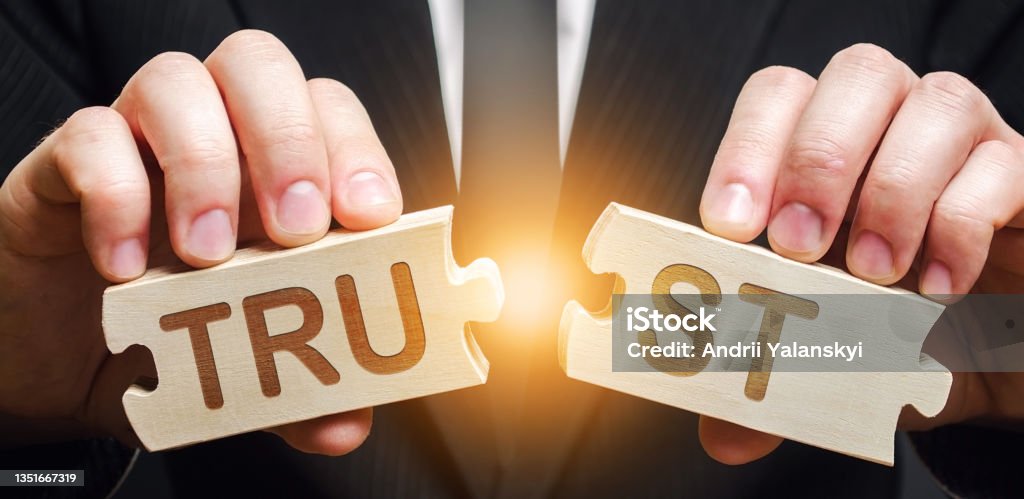 A man shares two puzzles with the word Trust. Violation of agreements and promises. Lose credibility. Failed to maintain professional reputation. Lie and cheat. Bad consequences. Not trustworthy Trust Stock Photo