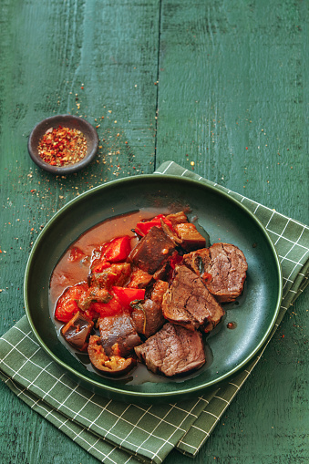 Grilled steak with vegetable salsa. Close-up composition on dark green background.