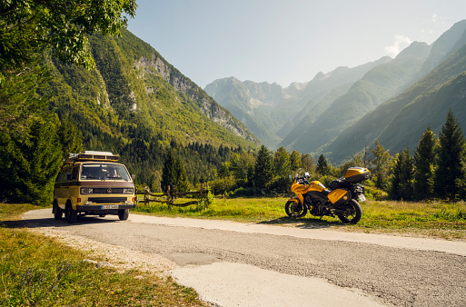 Bovec, Slovenia - August 31, 2017: Motorcycle journey through beautiful mountain roads near Bovec, Slovenia. Motorcycle rider and a vintage van on the way. No people seen on the picture. Beautiful green valley and mountains on the background.