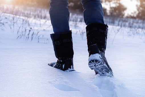 A man walking on a snowy road. Boots close-up.