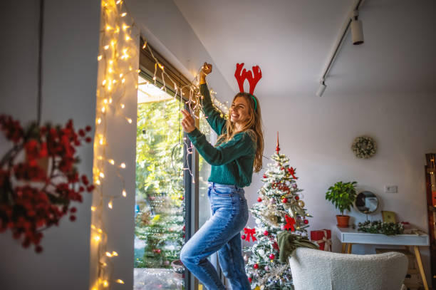 young woman decorating home for the upcoming holidays - decorating imagens e fotografias de stock