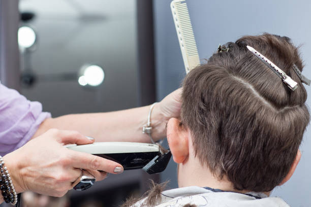 Professional hairdresser uses hair clipper for fringing hair, horizontal Professional hairdresser uses hair clipper for fringing hair, horizontal, closeup teenager boy haircuts stock pictures, royalty-free photos & images
