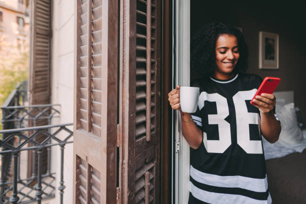 istock Cheerful woman texting at the balcony 1351675243