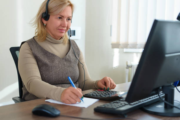 istock Happy businesswoman working using a calculator in a desk at office. She is using calculator and writing numbers down. Concept of accounting work. Shallow depth of field. 1351676887