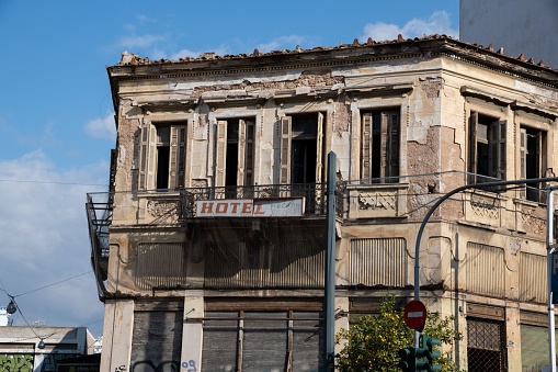 Piraeus, Greece - 10 30 2021: front facade of a rund down abandoned Hotel building in a downtown street of Piraeus