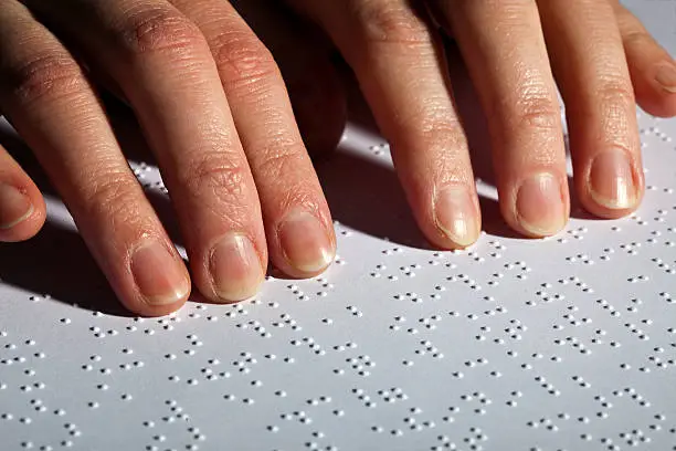 blind woman reading a document with printed text and braille.