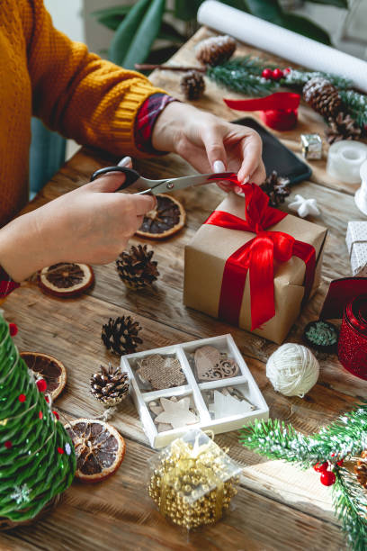 istock Young woman wrapping christmas present on table with new year decorations 1351690622