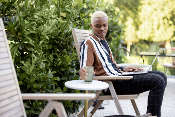 istock Latin man using laptop on lounger at house garden 1351692928
