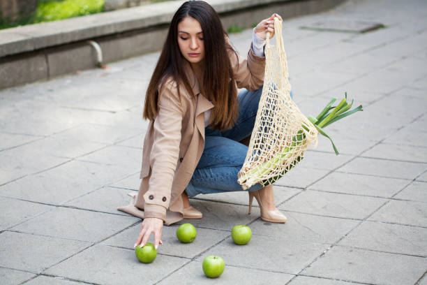 istock Young woman dropping groceries on sidewalk 1351693373