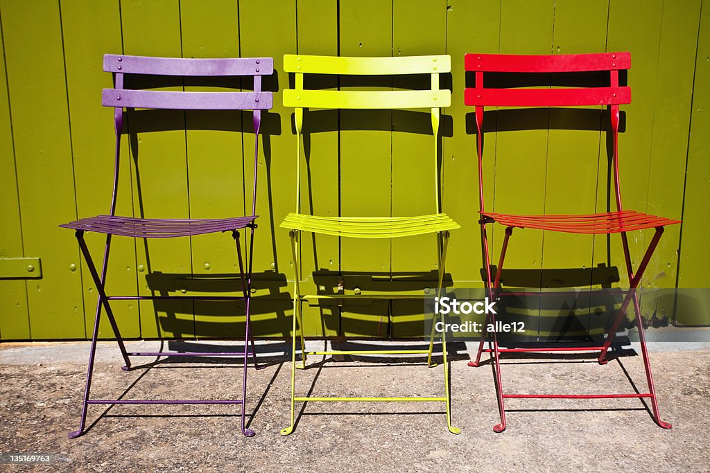 Stühle in einer Zeile gegen green door - Lizenzfrei Bunt - Farbton Stock-Foto