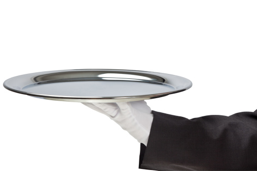 Butler holding empty silver tray in gloved hand.