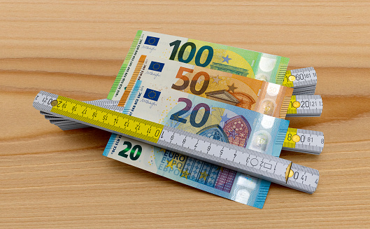 Euro banknotes clamped in a folding rule on a wooden board