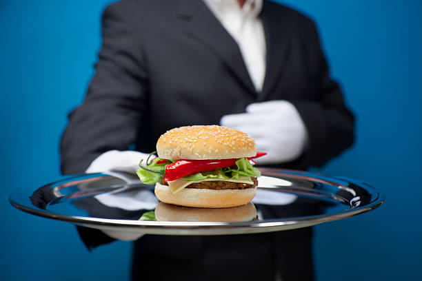 istock White gloved butler serving hamburger on silver tray 135169925