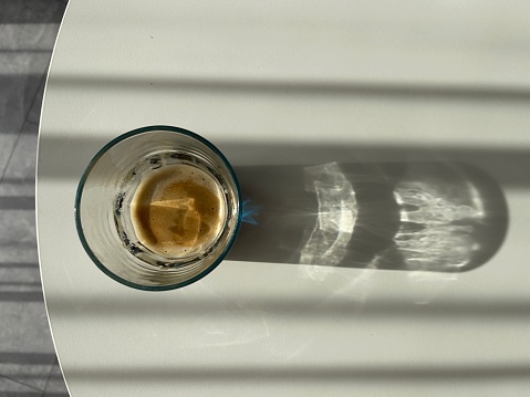 a glass of coffee lit by the sun on a white background top view