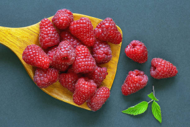 istock Fresh ripe raspberries in wooden spoon on dark table 1351711252