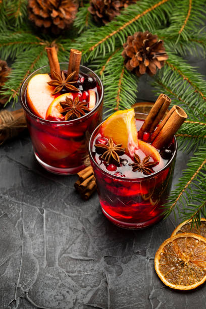 zwei gläser weihnachts-glührotwein mit dekoration, orange, zimt und tanne auf rustikalem hintergrund - glühwein stock-fotos und bilder