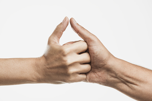 Two hands are playing thumb wrestle in front of white background.