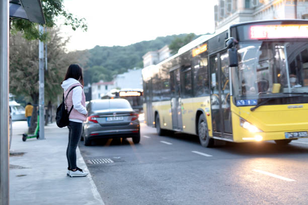 donna in attesa di autobus alla fermata dell'autobus. - transportation bus mode of transport public transportation foto e immagini stock