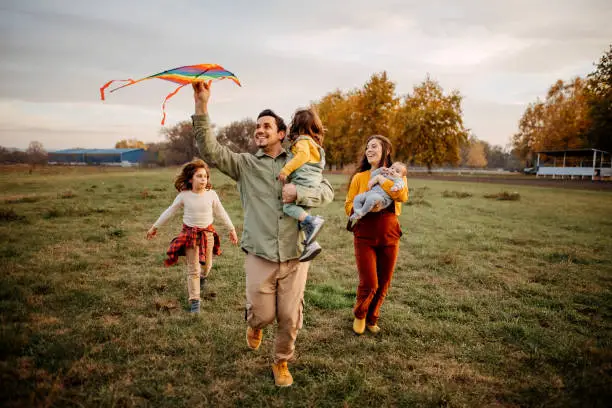 Family with three children enjoys a beautiful autumn day, children play with a toy flying dragon