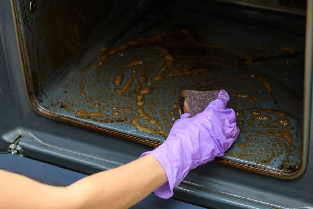 Home cleaning concept. A woman's hand washes with a sponge on a dirty oven. Close-up. Home cleaning concept. A woman's hand washes with a sponge on a dirty oven. Selective focus on hand oven stock pictures, royalty-free photos & images