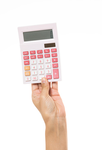 Hand is holding a pink calculator in hand in front of white wall.