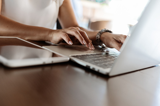 Close up of a woman hands typing in a laptop in a coffee shop