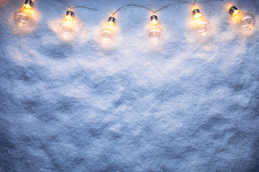 String lights on snow. Christmas and New Year winter holidays copy space background.