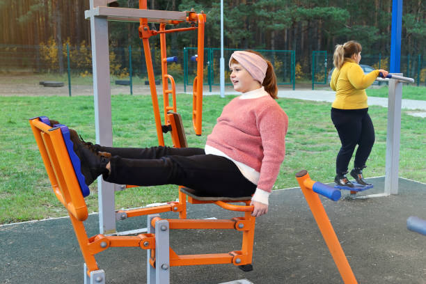 chubby mädchen führt sportübungen auf straßensimulatoren durch - child obesity stock-fotos und bilder
