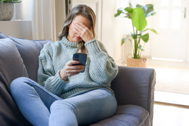 istock attractive middle aged woman sitting on the couch (negative emotions, smartphone)) 1351725107