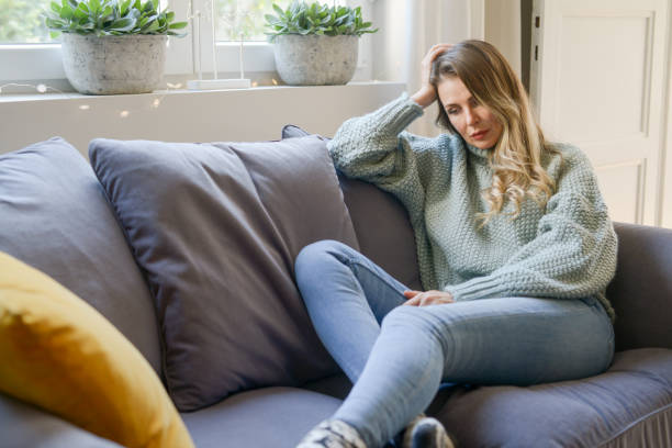 istock attractive middle aged woman sitting on the couch (negative emotions) 1351725953