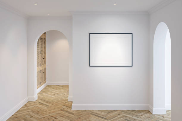 istock White lobby in modern classic style with a blank horizontal poster on a white wall, arched doorways, parquet floor, ceiling with recessed lights, wooden wardrobe in the background.Front view. 1351727881