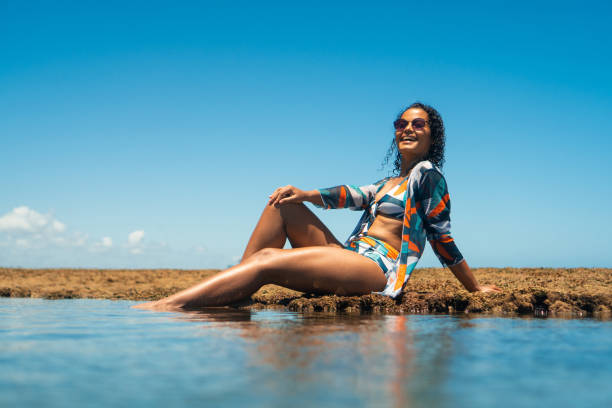 woman sitting on corals on tropical beach - 回教泳裝 圖片 個照片及圖片檔