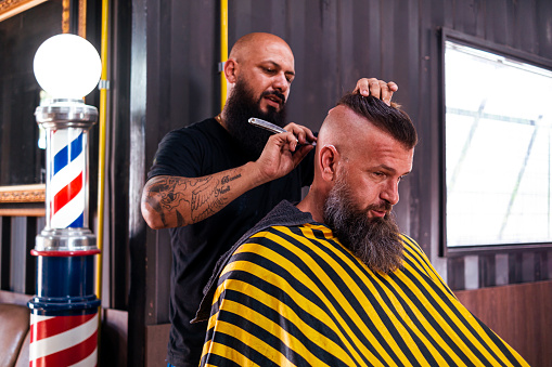 Beard man getting a haircut in a barbershop.