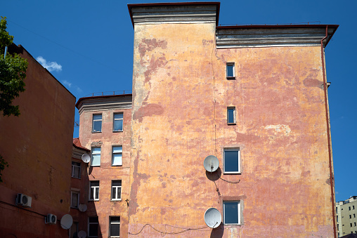 View of old german multistorey house, red yellow stucco wall, windows. Sunlight and shadow, blue sky. Kaliningrad, Russia