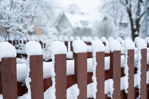 Close-up of wooden fence covered in snow during winter season.
