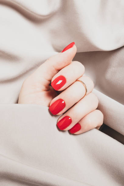 Female hand with bright red manicure on a background of beige fabric Female hand with bright red manicure on a background of beige fabric vibrant color lifestyles vertical close up stock pictures, royalty-free photos & images