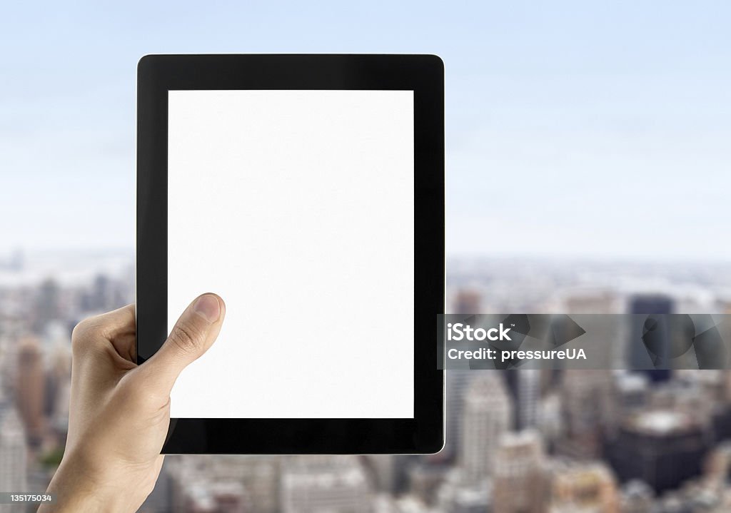 Hand Holds Blank Tablet PC Man hands are holding touch screen device with blank screen. Blurred cityscape with skyscrapers on background. Blank Stock Photo