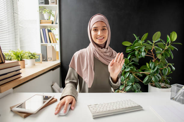 istock Happy young Muslim female waving hand to someone on computer screen 1351753206